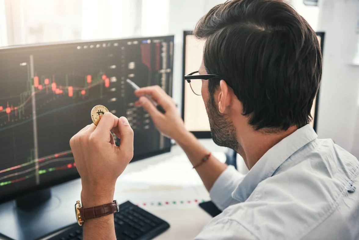  Back view of young professional trader in eyeglasses pointing on the data in the screen 