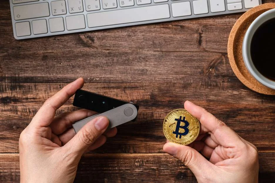  Tangan memegang dompet perangkat keras dan bitcoin 