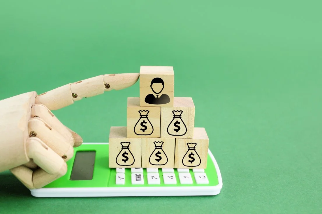  Wooden cube with a man's icon above and a stack of money below 